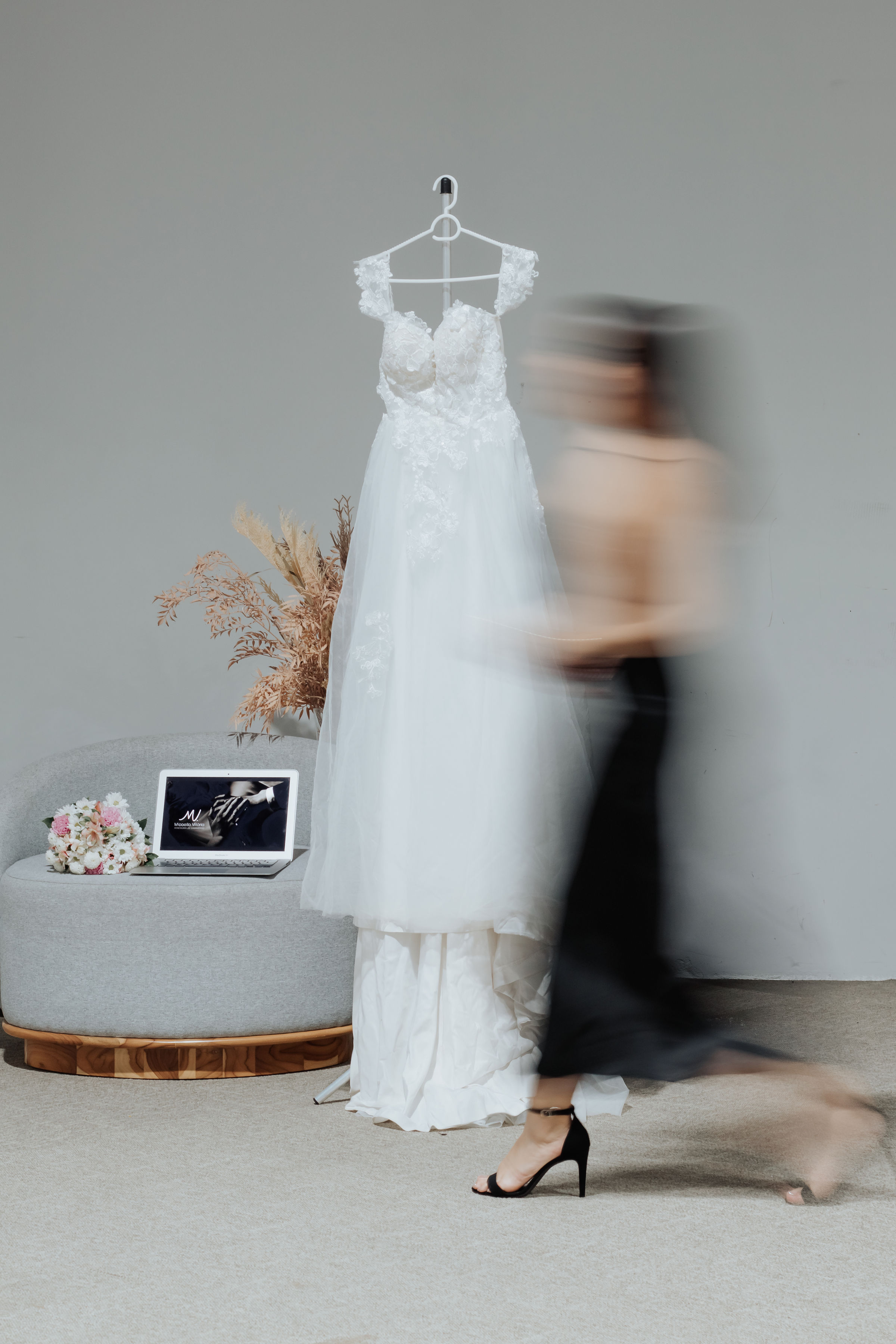 Mulher em movimento passando na frente de um vestido branco de noiva
